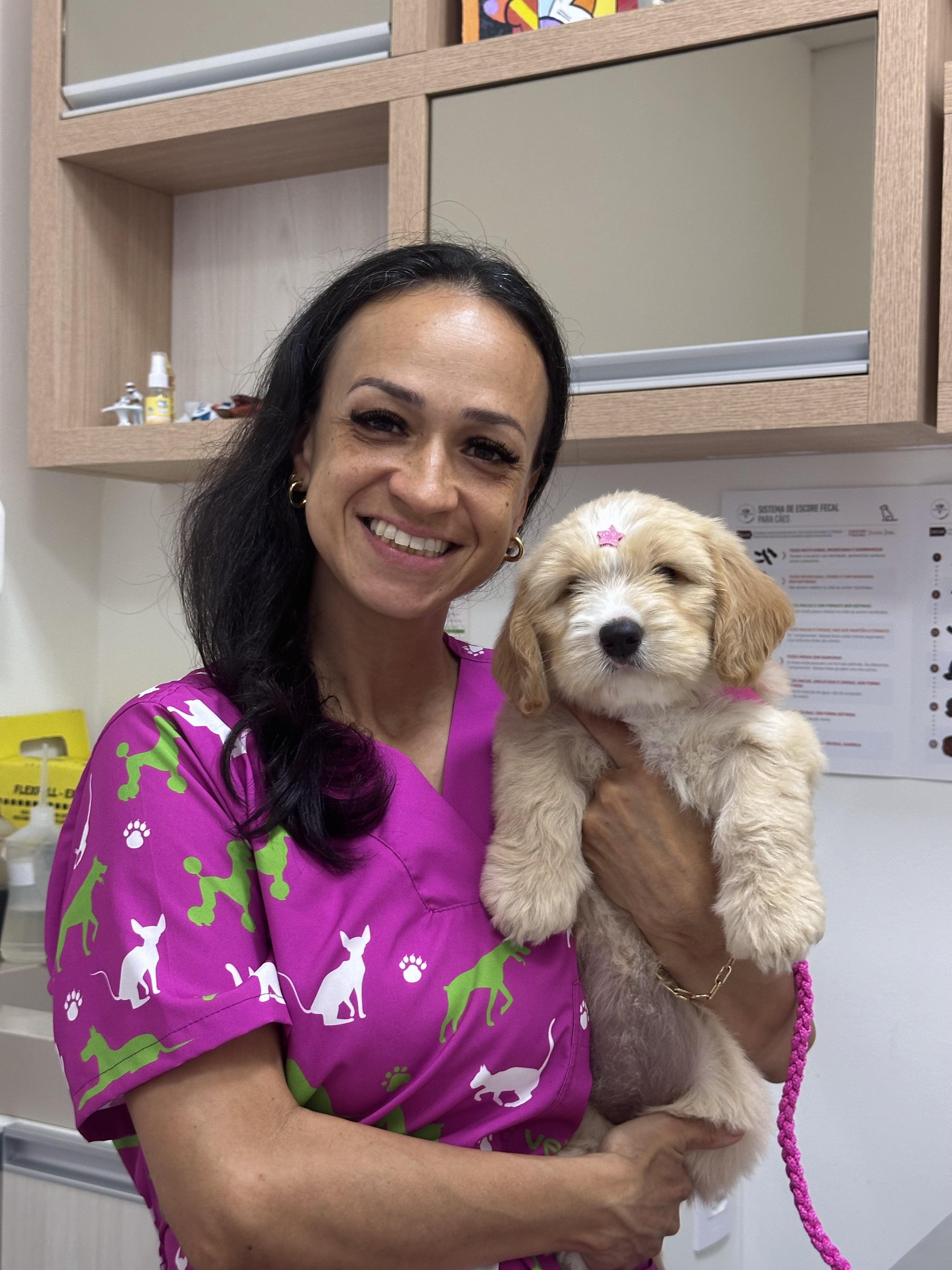 Veterinária da Vetbichos segurando filhote dourado em sala de exames